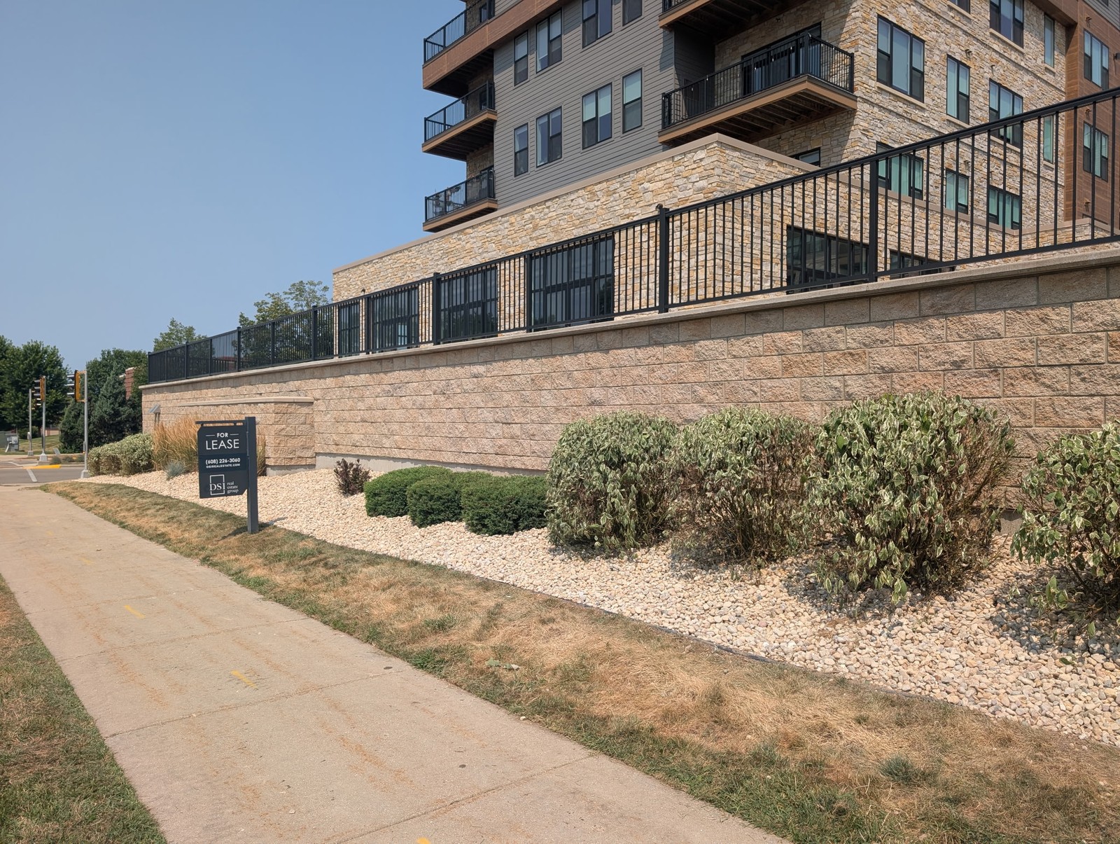 Rock beds and shrubs along a sidewalk below an apartment building