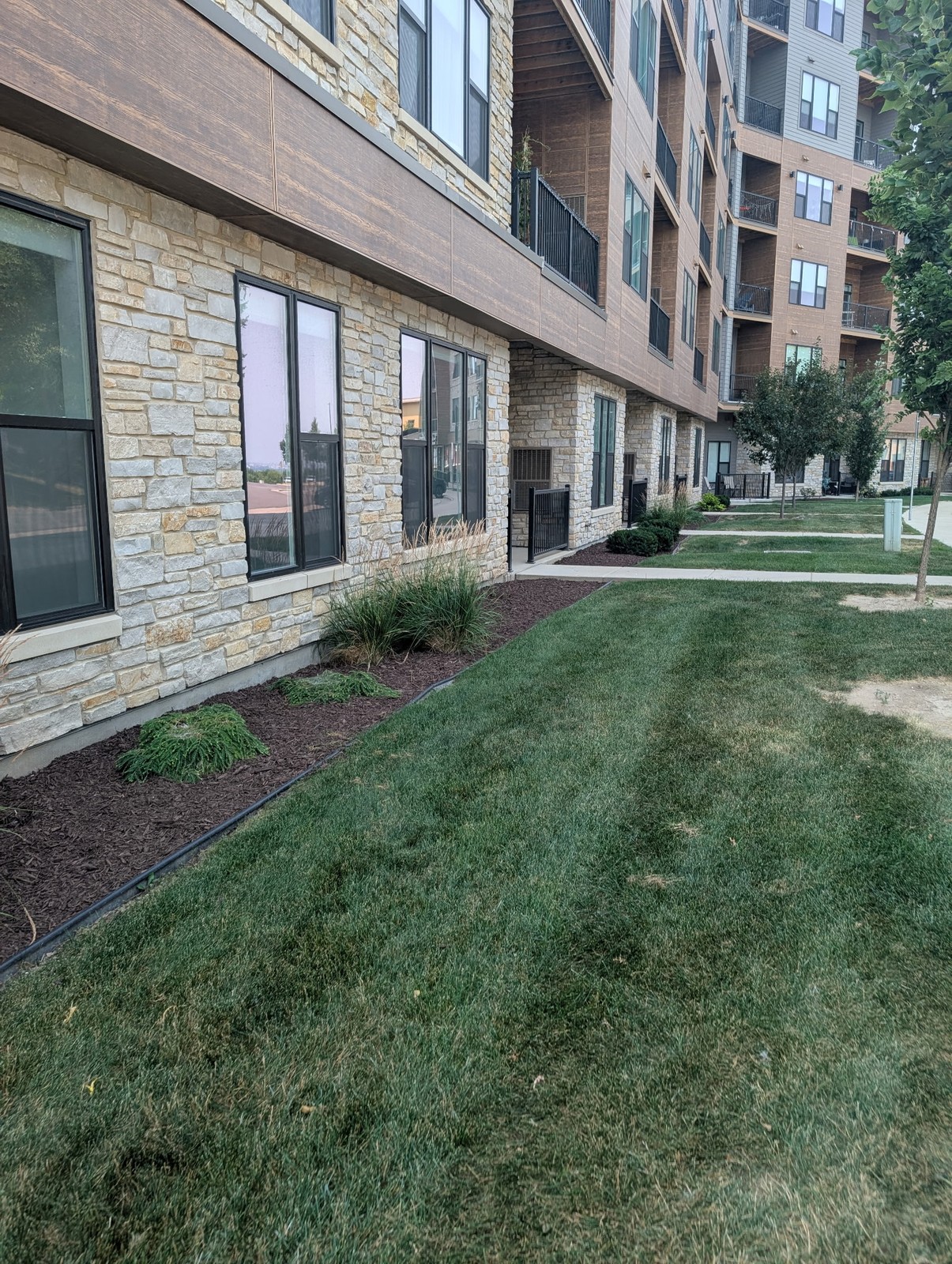 Fresh mulch beds along a stone apartment building