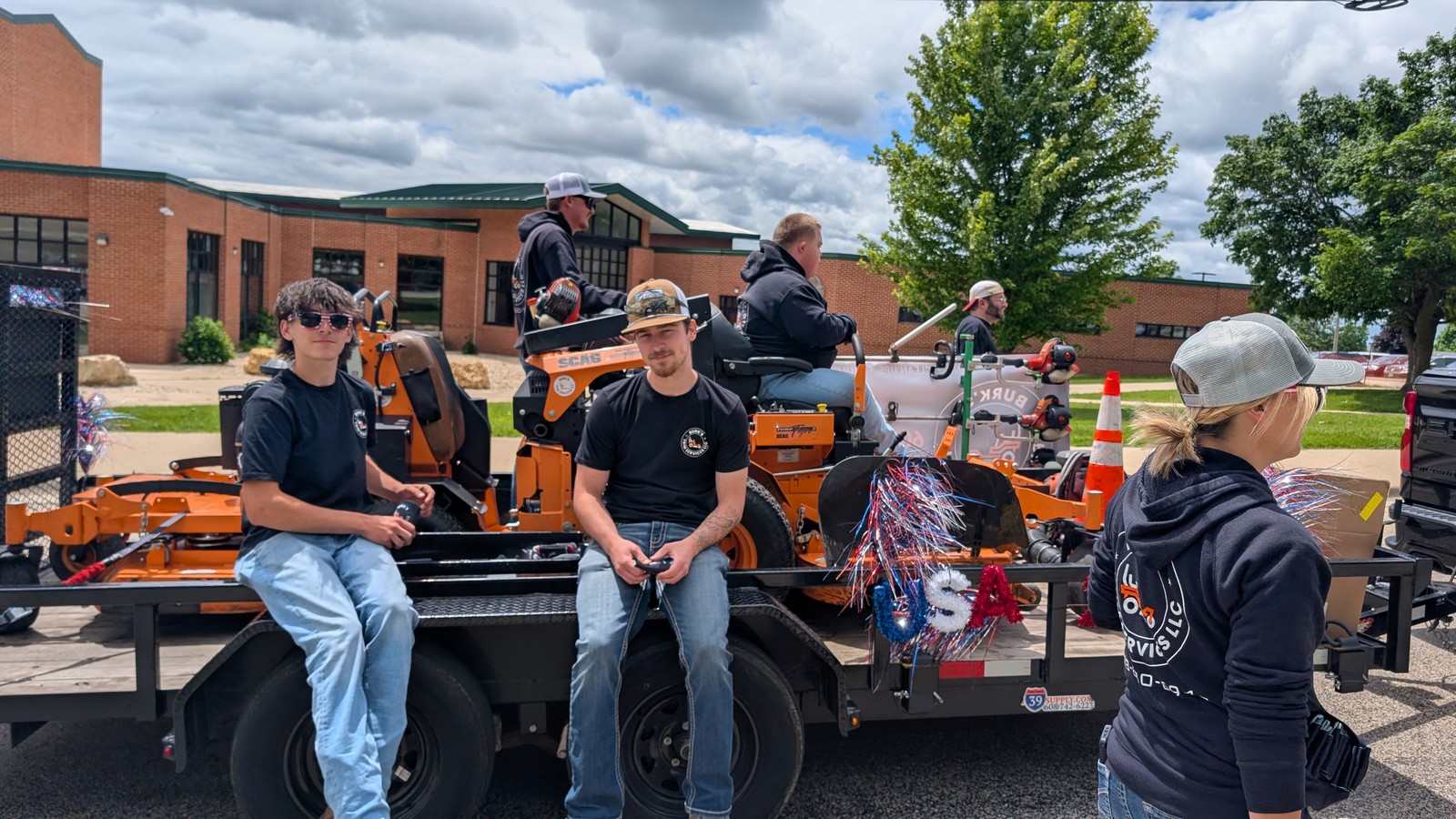 Burk's crew riding on the equipment trailer with the mowers