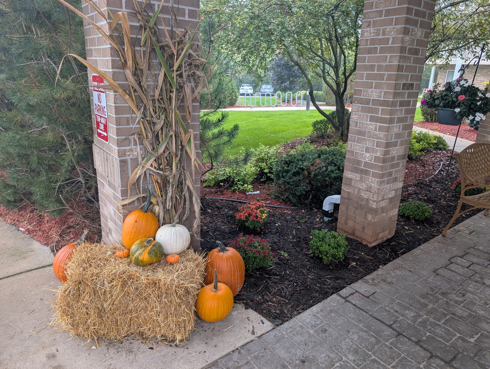 Pumpkins and a straw bale at the foot of a pillar wrapped in corn stalks