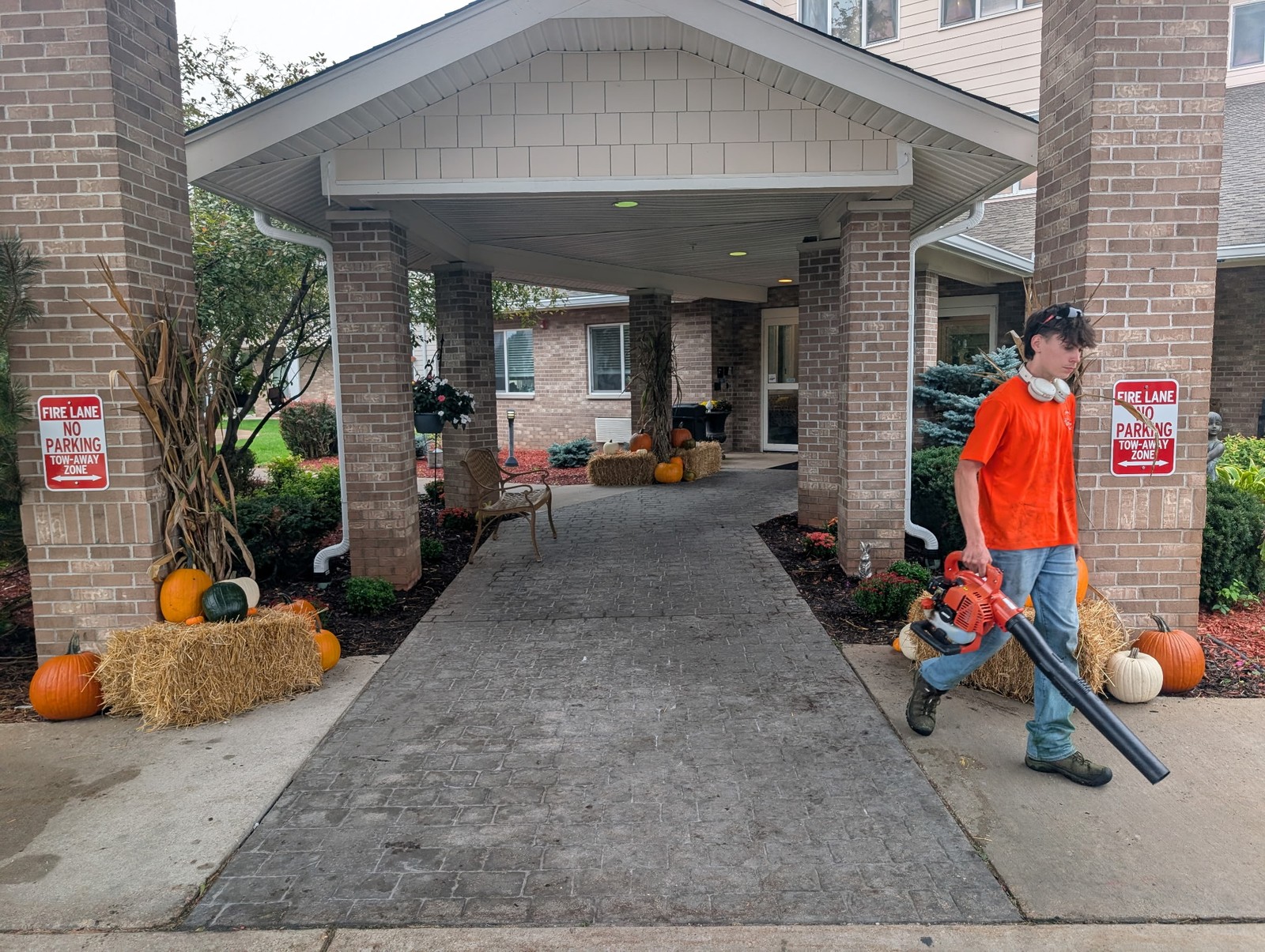 Crew member blowing off the walkway under a fall-decorated entrance