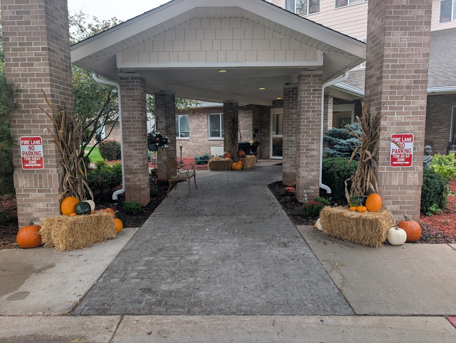 Building entrance decorated for fall with corn stalks, straw bales, and pumpkins
