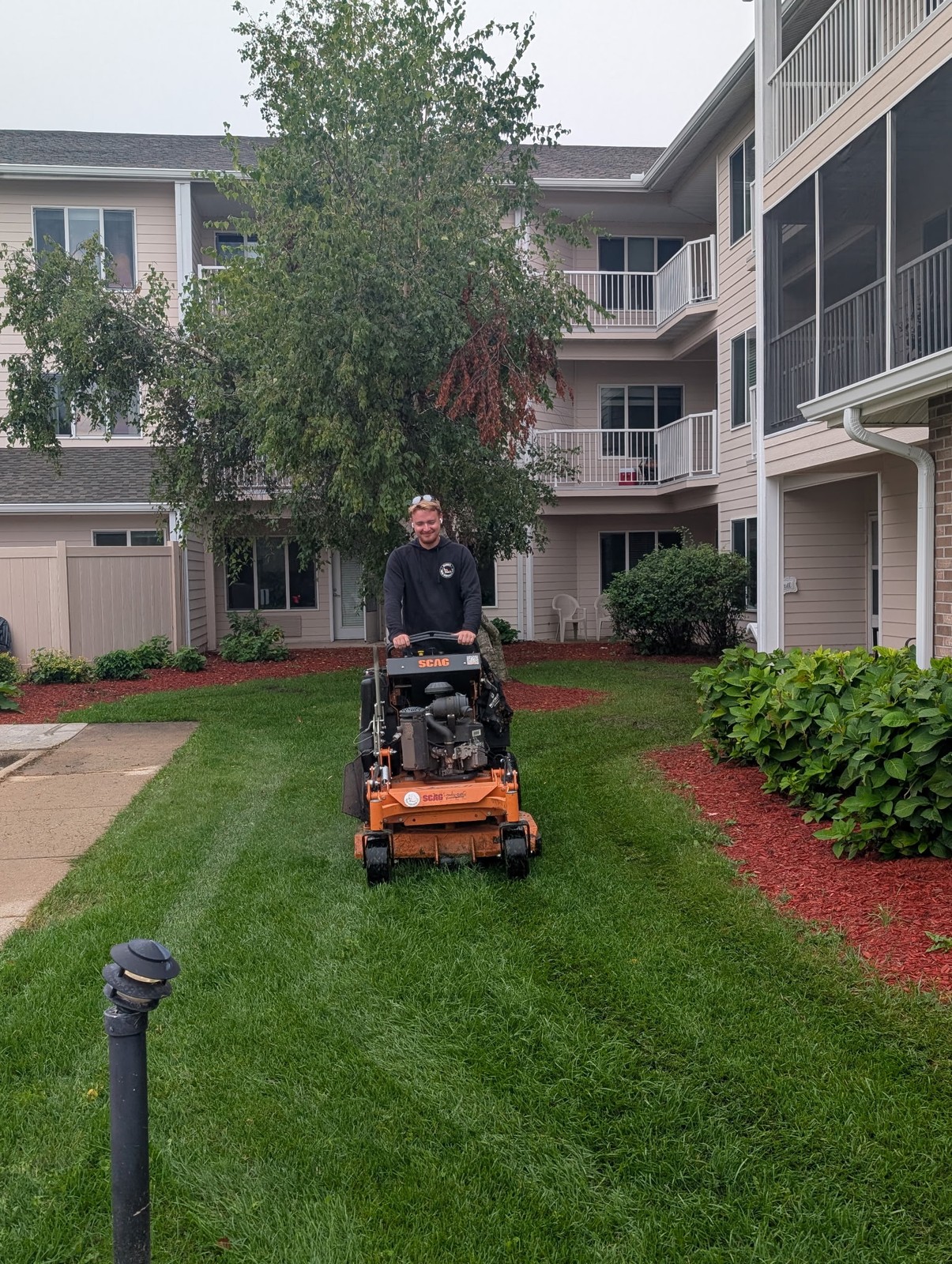 Crew member mowing a striped lawn between condo buildings