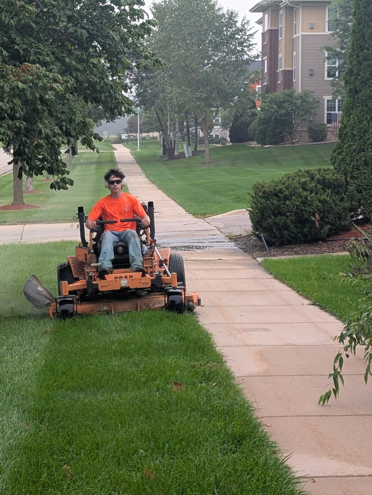 Crew member mowing along a sidewalk at an apartment complex